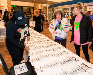 People collecting numbered packets from a table covered with envelopes at an organized event.
